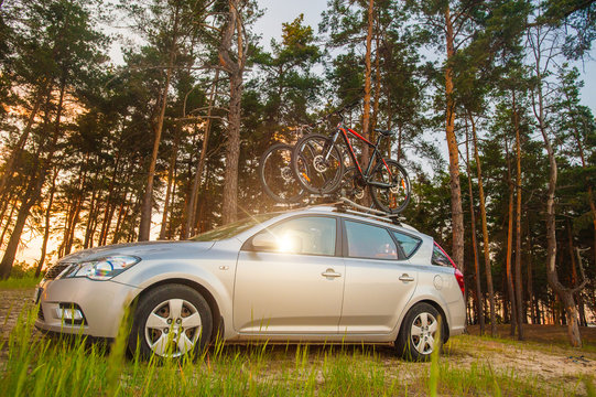 Family car is transporting bicycles on rack. Bikes on the trunk. Summer vacation. Forest road travel friends