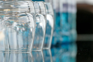 Glasses on a glass table with bottles of water in background