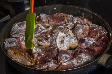 The cook prepares the fried liver in a frying pan on an induction cooker