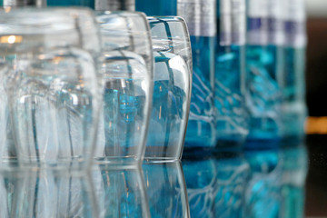 Glasses on a glass table with bottles of water in background