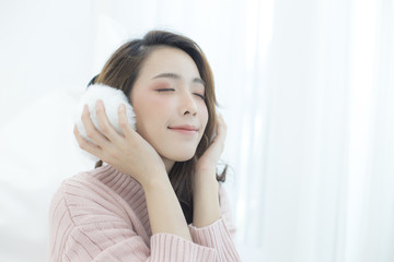 Attractive Asian Girl wearing sweater listen music with smile at home. Woman with winter concept.