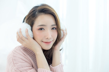 Attractive Asian Girl wearing sweater listen music with smile at home. Woman with winter concept.