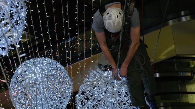Industrial climber mounts Christmas decorations in the unsupported space in the shopping center