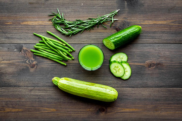 Green detox beverage with cucumber, asparagus, zucchini on dark wooden background top view