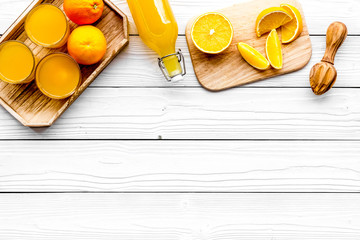 Make orange juice. Juicer, beverage in bottle and glasses near slices of oranges on white wooden...