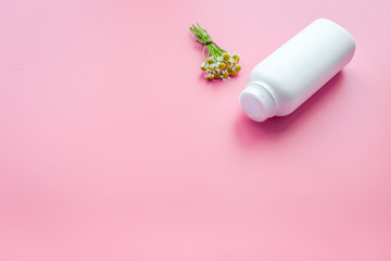 Soft bath cosmetics for kids with chamomile. Bottle on pink background copyspace