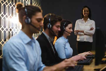 Business executives with headsets using computers at desk