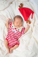 Asian baby boy wearing red Santa Claus outfit with reindeer hat.