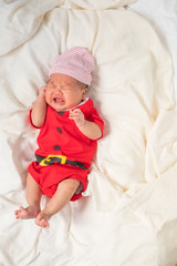 Asian baby boy wearing red Santa Claus outfit.