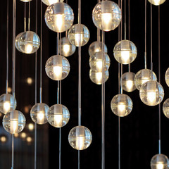  lighting balls on the chandelier in the lamplight,  light bulbs hanging from the ceiling, lamps on the dark background, selective focus, horizontal.