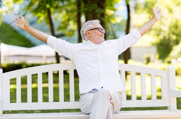 Fototapeta premium happy senior man sitting on bench at summer park