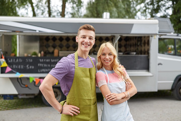 Naklejka premium happy couple of young sellers at food truck