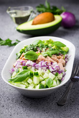 Fresh avocado tuna cucumber salad on concrete background. Selective focus, copy space. 