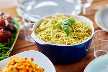 pasta with basil in bowl and other food on table