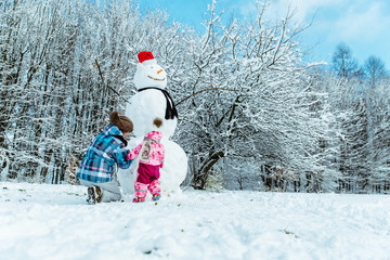Fototapeta na wymiar mother with daughter making snowman