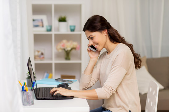 woman with laptop calling on smartphone at home