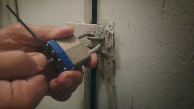 Closeup locksmith lockpicker picking opening lock on old door. 4K UHD.