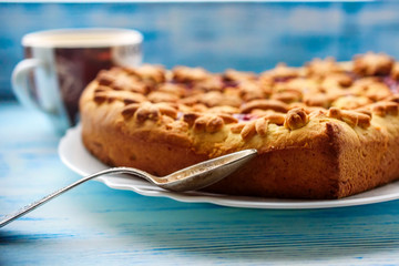 pie with strawberry jam and delicious coffee on an old wooden background