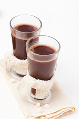 Warm cocoa in glasses with marshmallow, crocahet decorations, brown and beige napkins on white wooden background. Hot chocolate. Sweet drink. Close up photography. Vertical banner