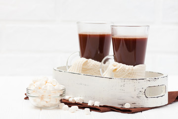 Warm cocoa in glasses with marshmallow, crocahet decorations, brown and beige napkins on white wooden background. Hot chocolate. Sweet drink. Close up photography. Hoizontal banner