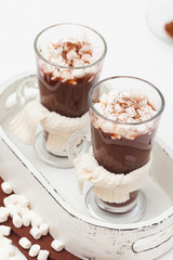 Warm cocoa in glasses with marshmallow, crocahet decorations, brown and beige napkins on white wooden background. Hot chocolate. Sweet drink. Close up photography. Vertical banner