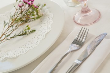 Flower kept over an embroidery napkin plate with cutlery