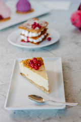 Cheesecake with red currant berries on white plate.