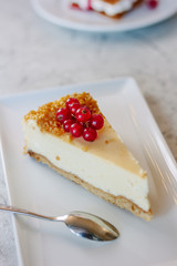 Cheesecake with red currant berries on white plate.