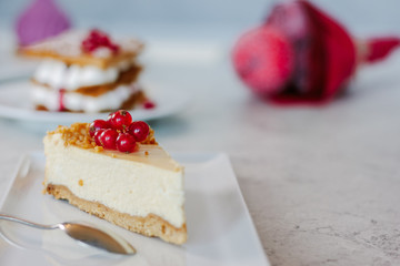 Cheesecake with red currant berries on white plate.
