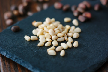 Pine nuts on black kitchen board over the wooden table.