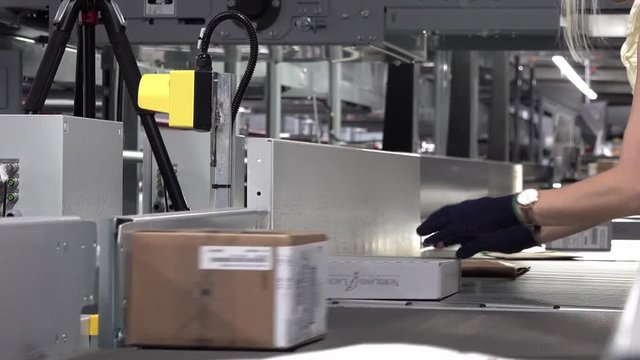 Lady correcting parcels on conveyor - time lapse