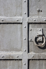 Old metal door close-up with round handle and grille