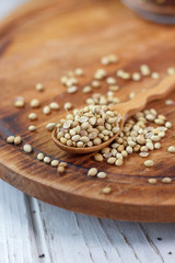 Coriander seeds in a wooden spoon over kitchen board.