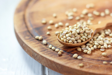 Coriander seeds in a wooden spoon over kitchen board.