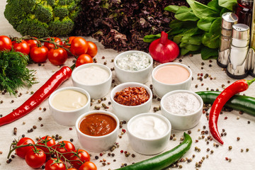 Set of sauces on white wooden background. Top view.