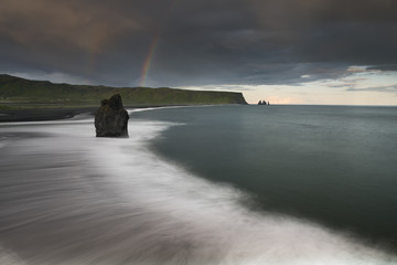 Reynisfjara black sand beach in Iceland with the rainbow