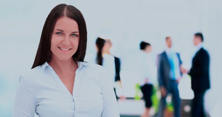 Successful business woman standing with her staff in background 