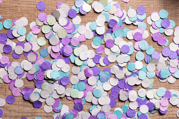 Obraz na płótnie Canvas Carnaval party background concept. Space for text, copyspace. Colorful confetti spread over wooden table.