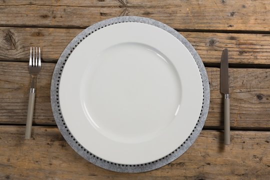 Plate with fork and butter knife on wooden table