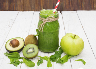 healthy green smoothie with banana, spinach, avocado and kiwi in a glass bottles on a rustic