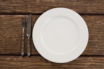 Plate with fork and butter knife on wooden table