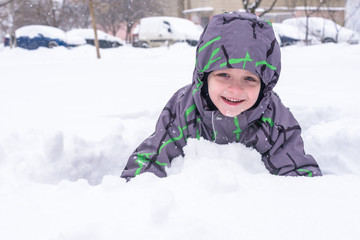 a little child looks out of the snow or pieces of ice. A child plays with snow