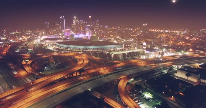 Aerial view city traffic freeway interchange night  downtown Los Angeles skyline