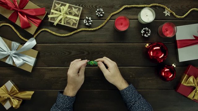 Man opens candy, eats it and throws wrapper on Xmas decorated desk, top down shot