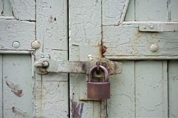 Green wooden gate of old warehouse, locked with padlock