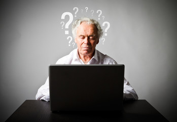 Old man using a laptop. Forgot password concept.