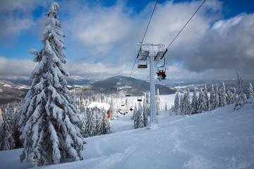Fototapeta na wymiar Ski lift in winter snowy landscape in mountains of spruce forest