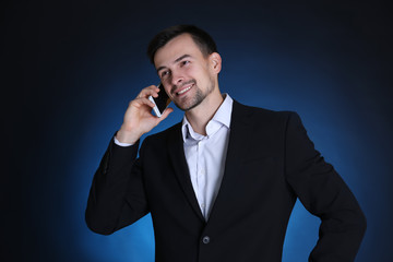 Man in formal suit talking on phone against dark background