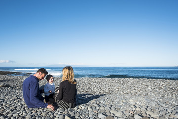 Mom and dad at the beach play and pamper their baby