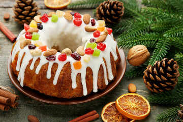 Bundt cake with fir-tree branches, dried oranges and cinnamon on wooden table